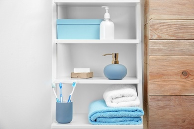 Photo of Towels, toiletries and soap dispenser on shelves in bathroom