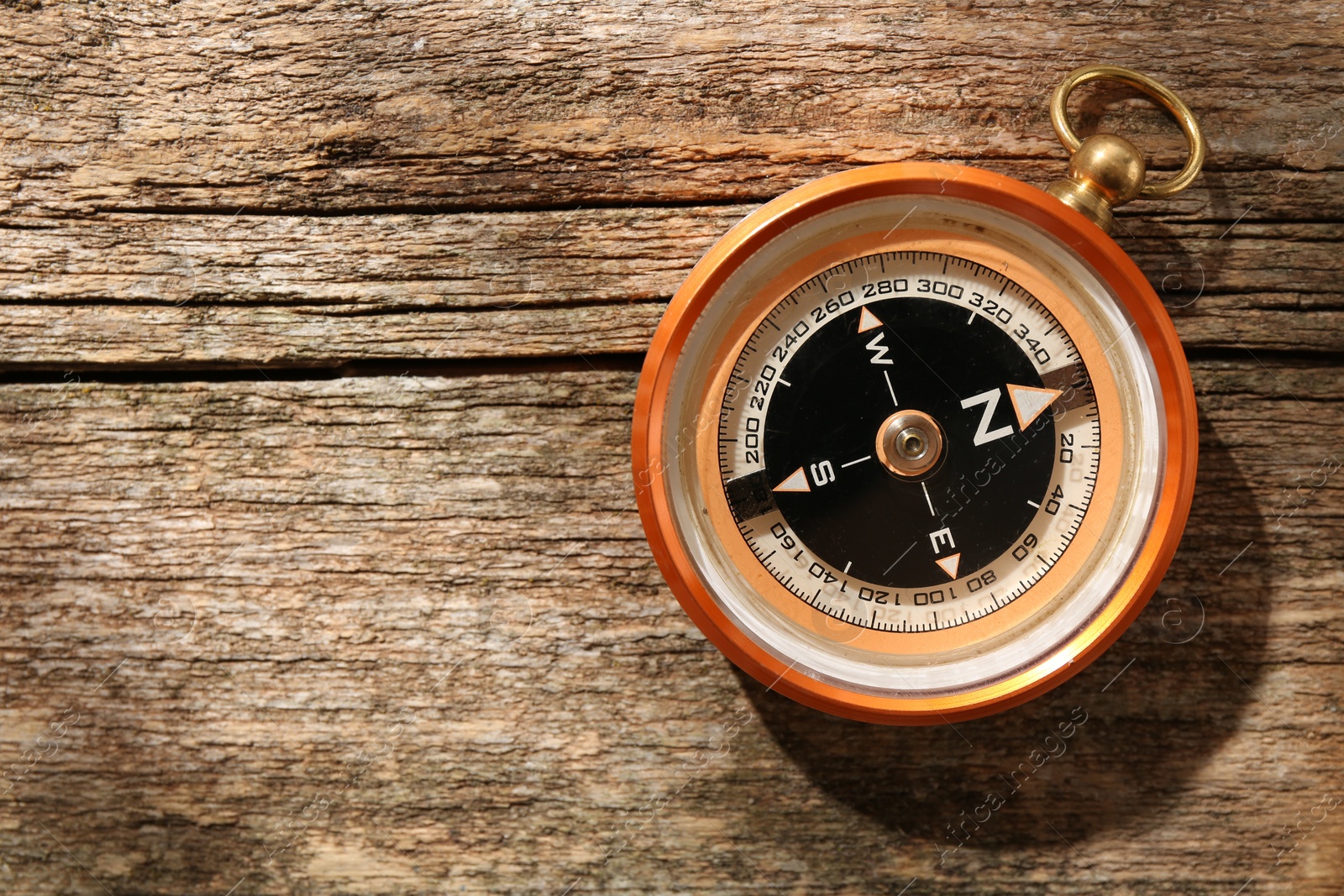 Photo of One compass on wooden table, top view. Space for text