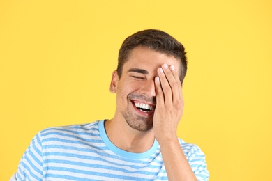 Photo of Portrait of handsome young man laughing on color background