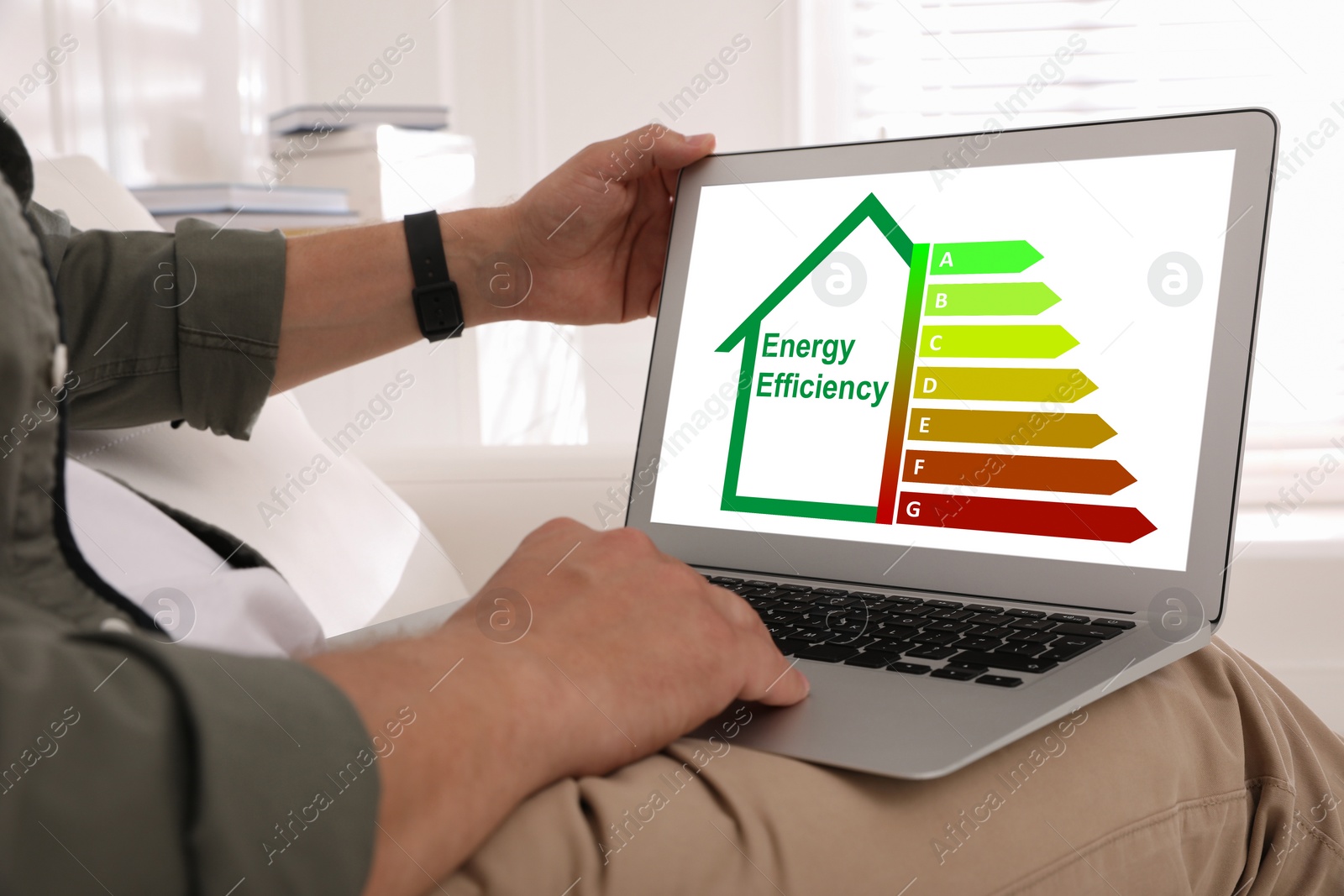 Image of Energy efficiency. Man using laptop with colorful rating on display at home, closeup