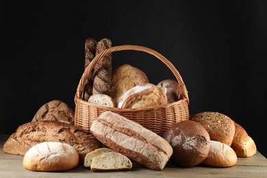 Photo of Wicker basket with different types of fresh bread on wooden table