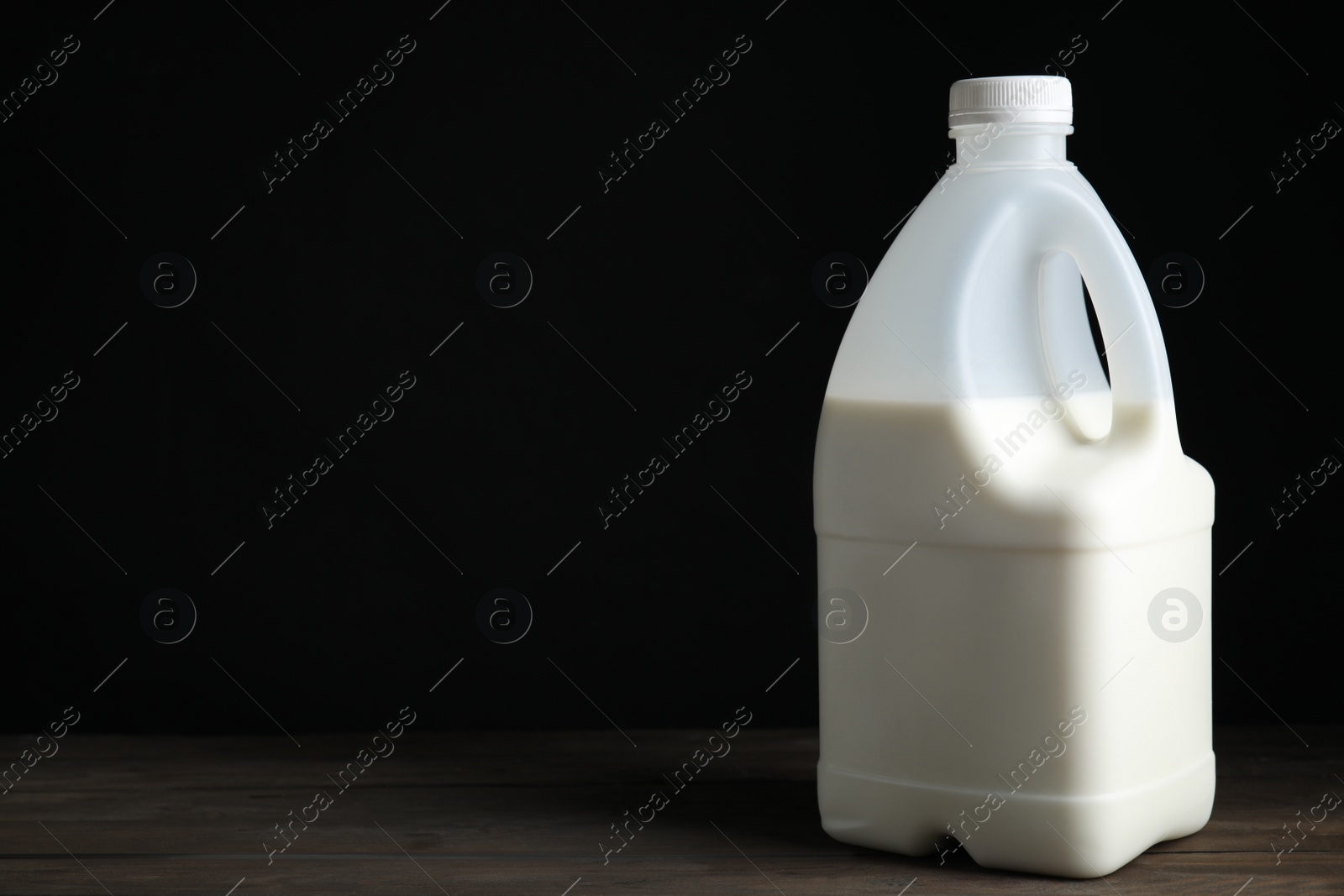 Photo of Gallon bottle of milk on wooden table, space for text