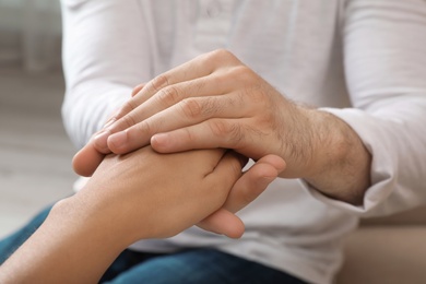 Photo of Man holding woman's hand indoors, closeup. Concept of support and help