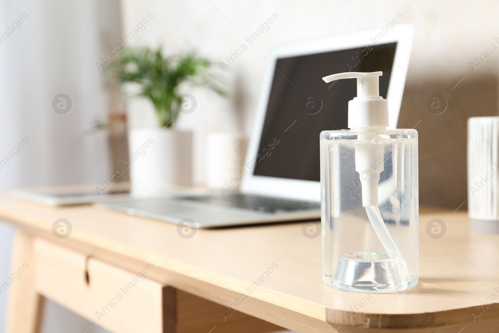 Photo of Dispenser bottle with antiseptic gel on table in office. Space for text