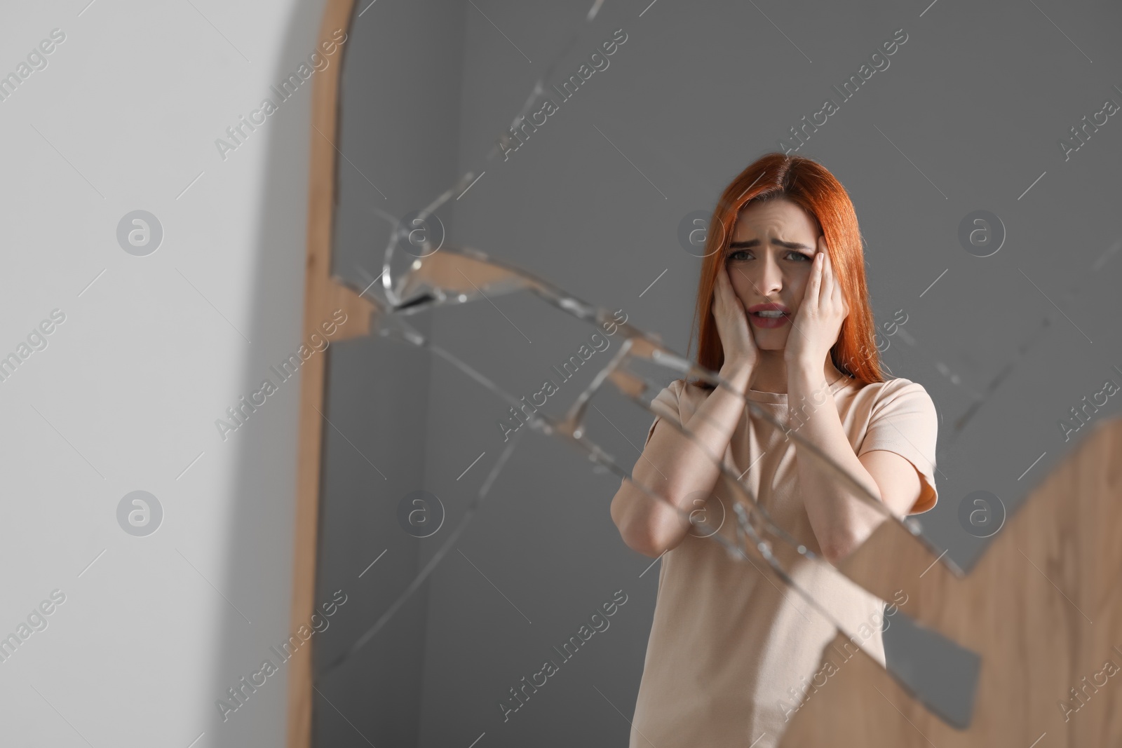 Photo of Mental problems. Emotional woman reflecting in broken mirror indoors