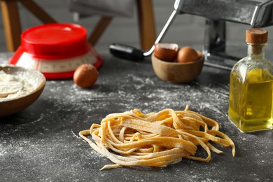 Photo of Homemade pasta, maker and ingredients on dark grey table