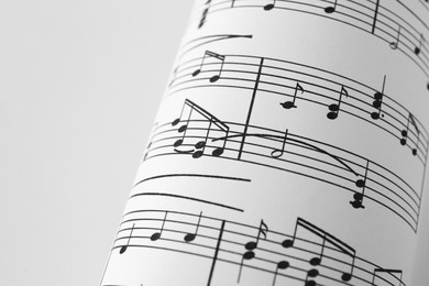 Photo of Rolled sheet with music notes on white background, closeup