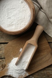 Photo of Baking powder in bowl and scoop on wooden table, flat lay