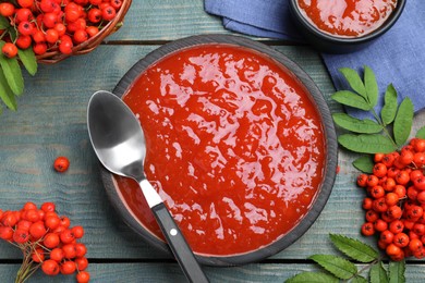 Flat lay composition with delicious rowan jam on light blue wooden table