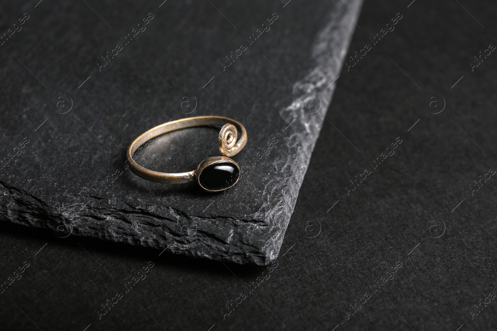 Photo of Elegant ring with stone on black background, space for text. Luxury jewelry