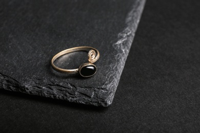 Photo of Elegant ring with stone on black background, space for text. Luxury jewelry