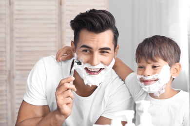 Photo of Father and son having fun while shaving in bathroom