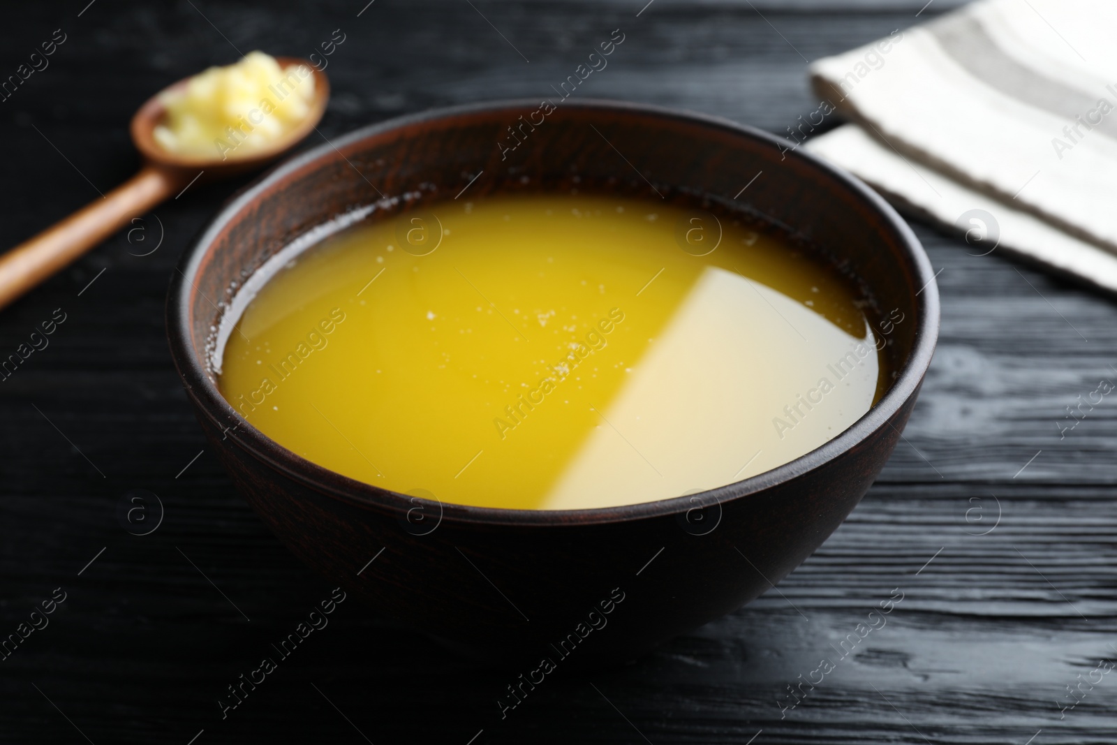 Photo of Bowl of Ghee butter on dark wooden table, closeup
