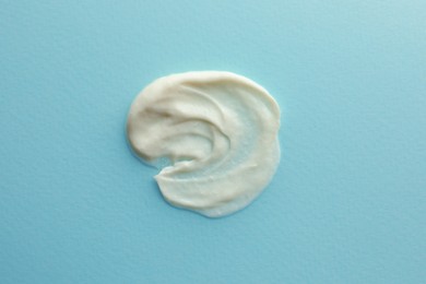 Photo of Sample facial cream on turquoise background, top view