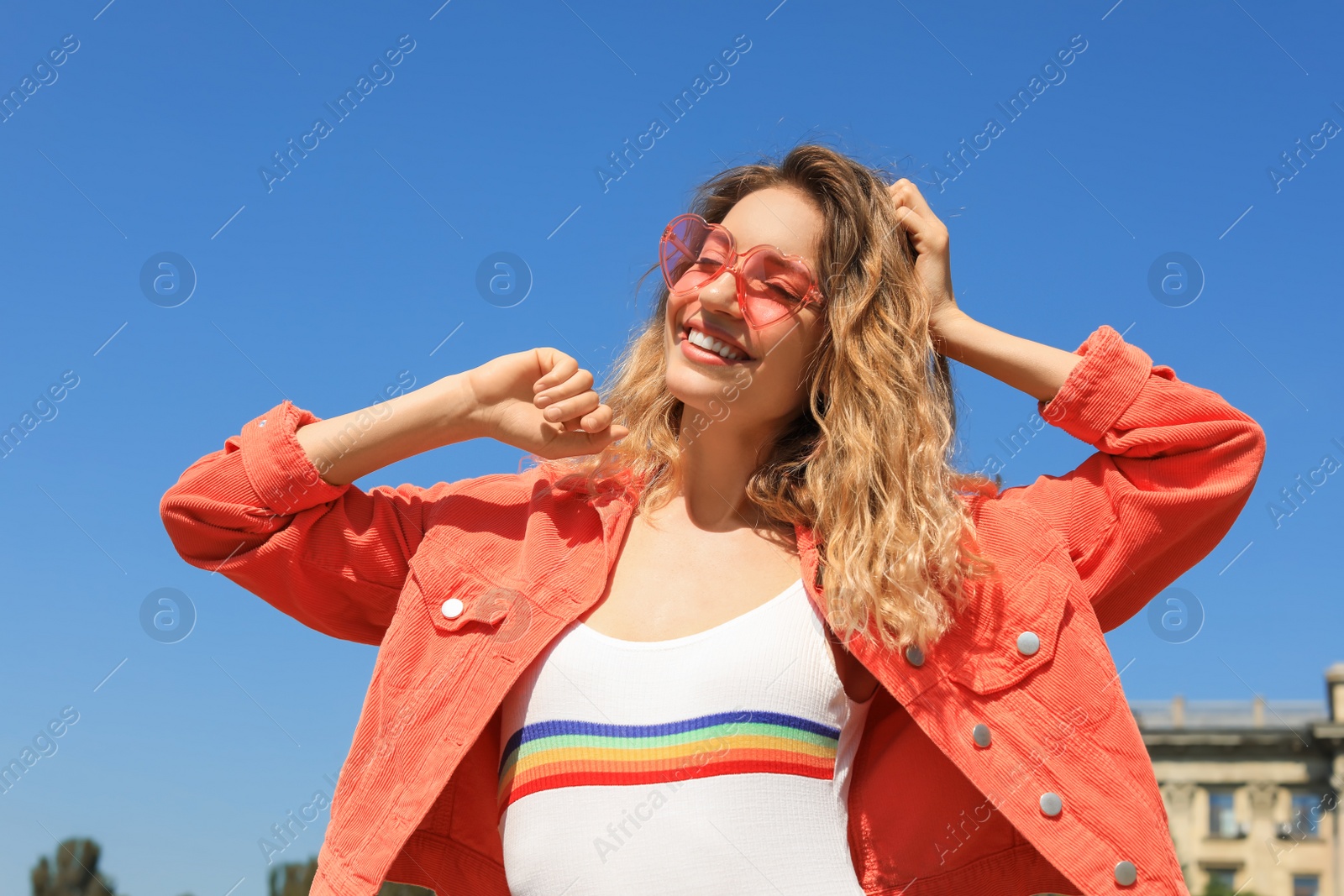 Photo of Portrait of happy young woman with heart shaped glasses in city on sunny day