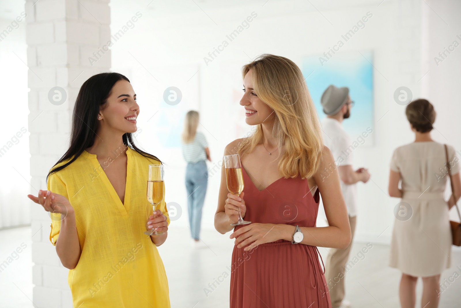 Photo of Young women with glasses of champagne at exhibition in art gallery