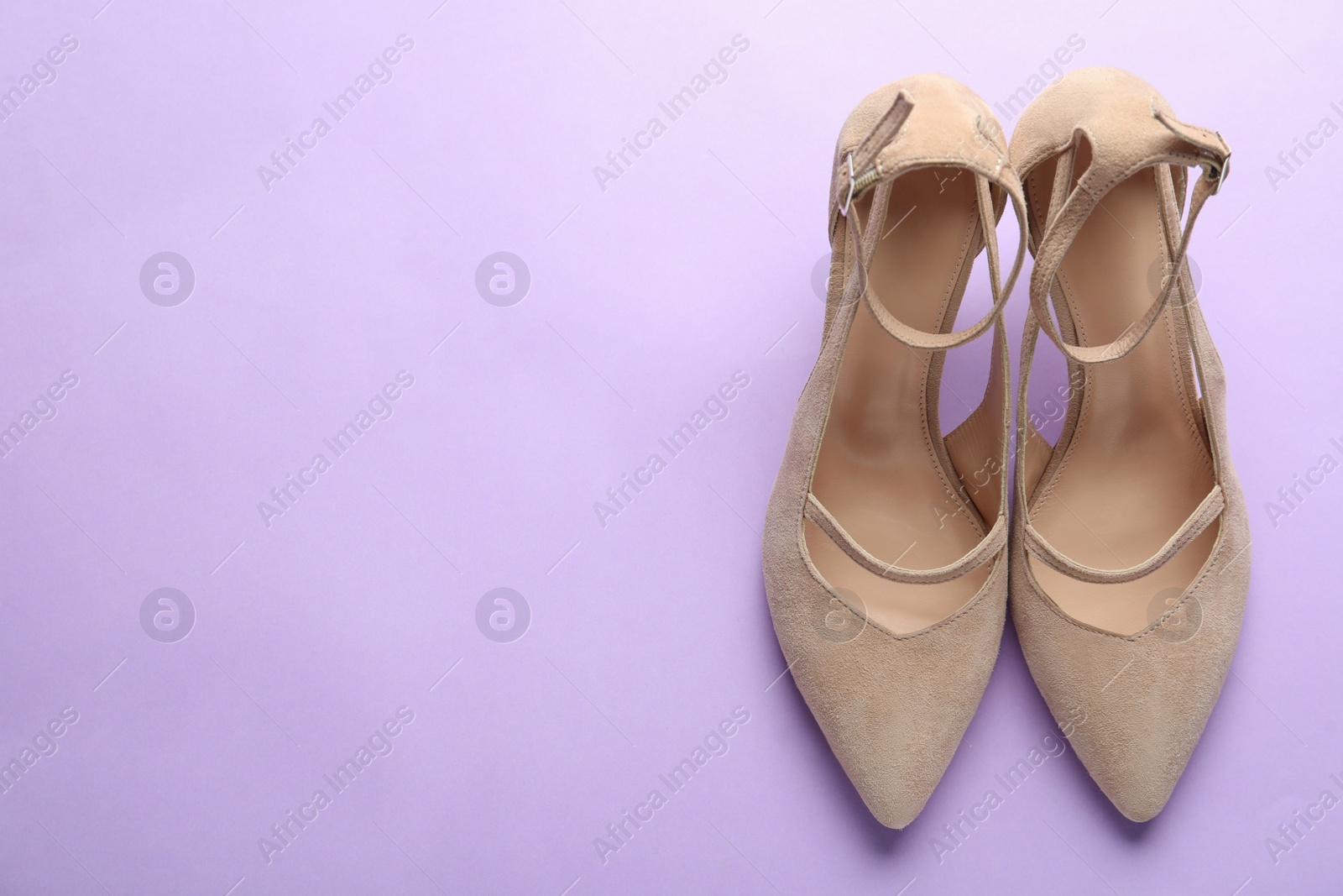 Photo of Stylish high heeled shoes on violet background, top view. Space for text