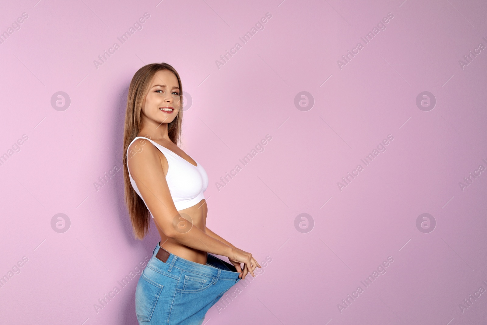 Photo of Slim woman in oversized jeans on color background. Healthy diet