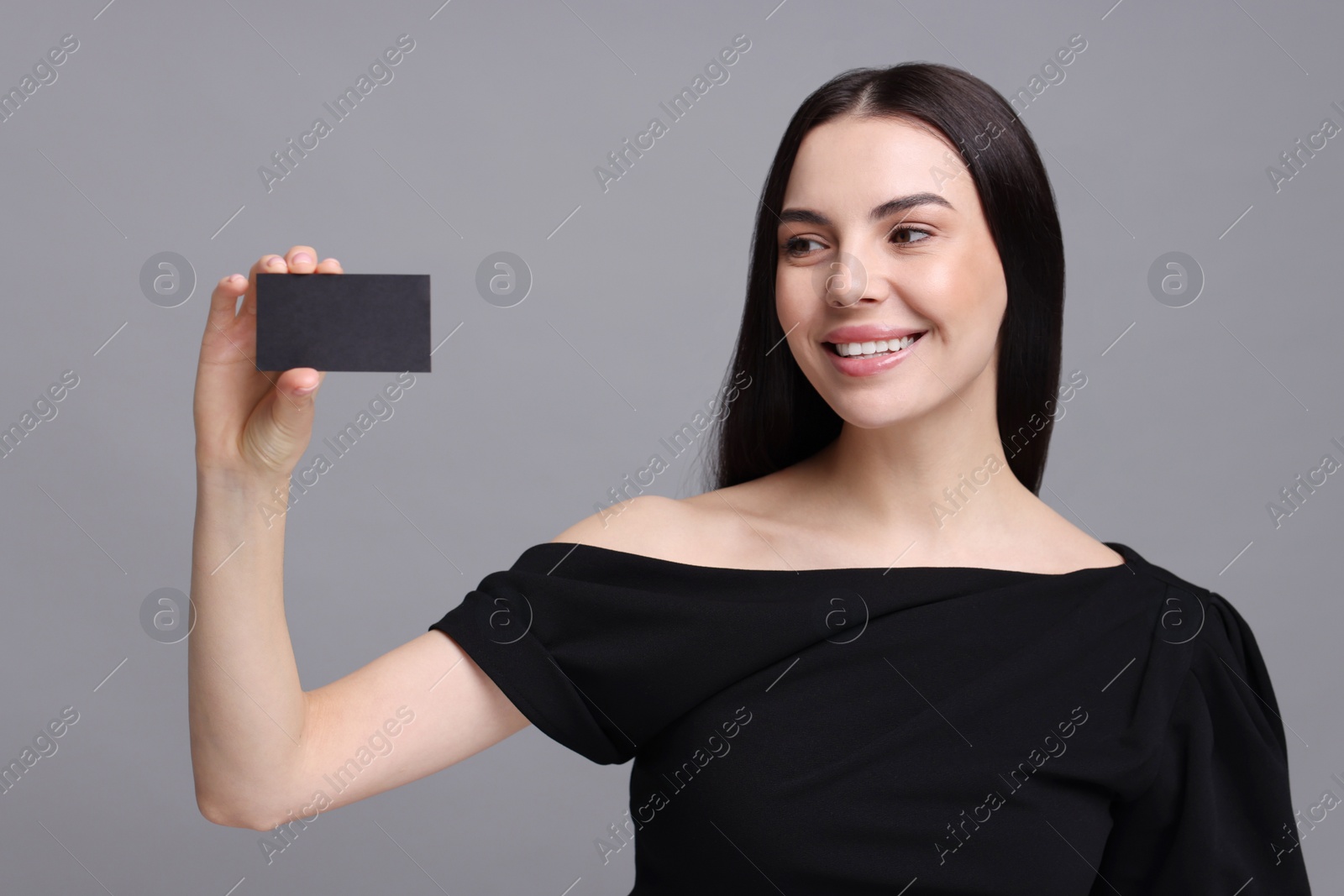 Photo of Happy woman holding blank business card on grey background
