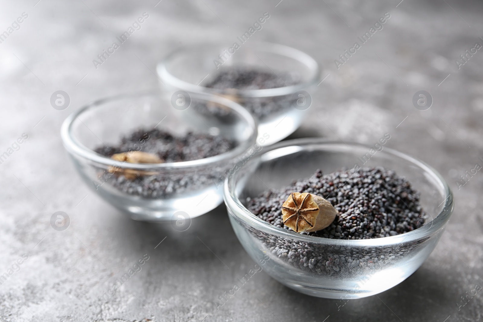 Photo of Bowls with dry poppy heads and seeds on table
