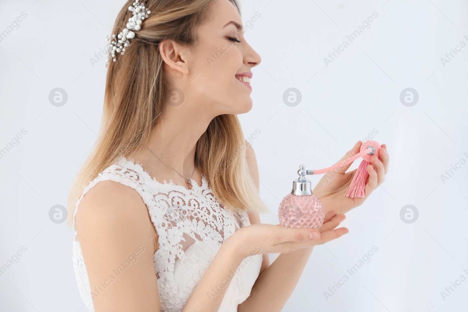 Photo of Beautiful young bride with bottle of perfume isolated on white