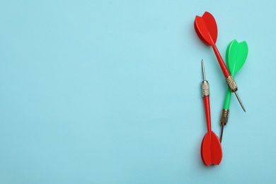 Plastic dart arrows on blue background, flat lay with space for text