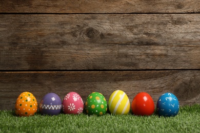 Photo of Decorated Easter eggs on green grass. Space for text