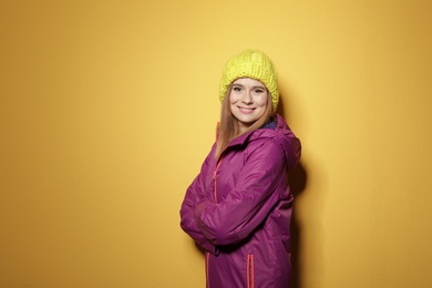 Photo of Young woman wearing warm clothes on color background, space for text. Ready for winter vacation