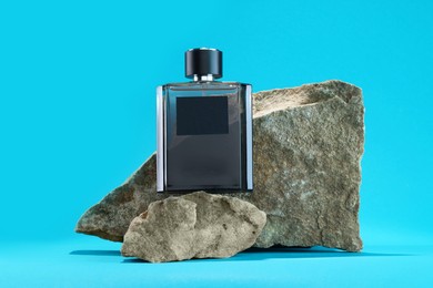 Stylish presentation of luxury men`s perfume on stones against light blue background