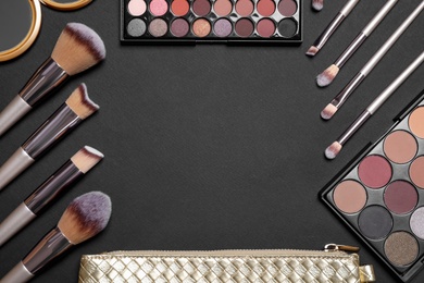 Photo of Flat lay composition with professional makeup brushes and eye shadow palettes on black background, space for text