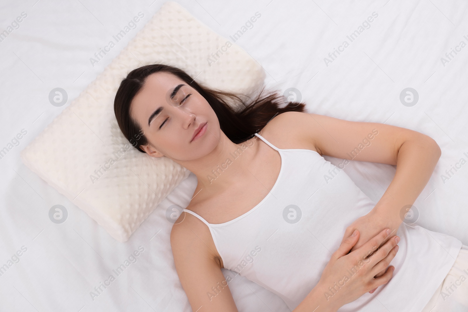 Photo of Woman sleeping on orthopedic pillow in bed, top view