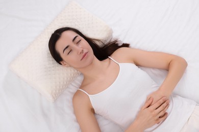 Woman sleeping on orthopedic pillow in bed, top view