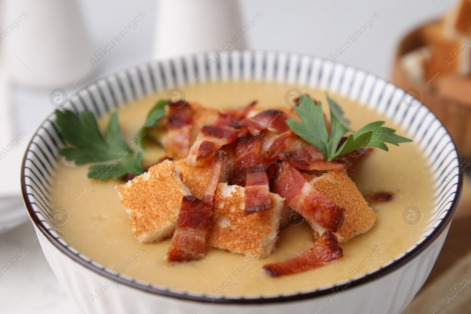 Photo of Delicious lentil soup with bacon and parsley in bowl on table, closeup