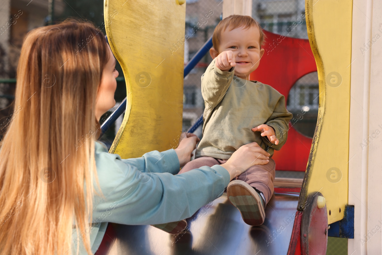 Photo of Nanny and cute little boy on slide outdoors