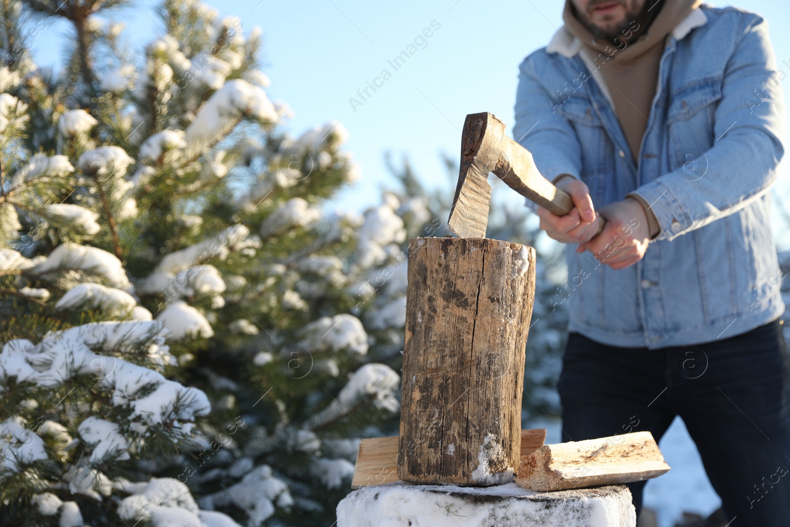 Photo of Man chopping wood with axe outdoors on winter day, closeup. Space for text