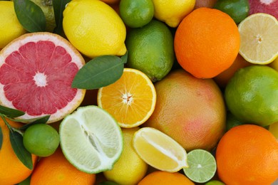 Photo of Different fresh citrus fruits and leaves as background, top view.