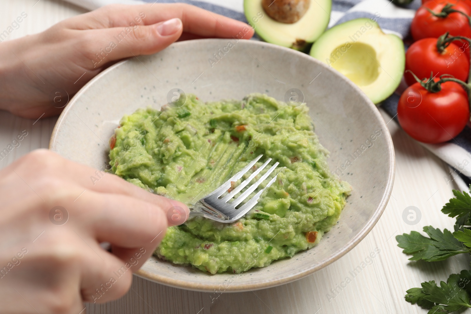 Photo of Woman preparing delicious guacamole at white table, closeup