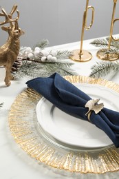 Photo of Stylish table setting with dark blue fabric napkin, beautiful decorative ring and festive decor, closeup