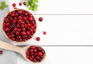 Photo of Fresh ripe cranberries and branches on white wooden table, top view. Space for text