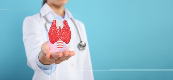 Image of Endocrinologist holding virtual thyroid gland on light blue background, closeup. Banner design with space for text