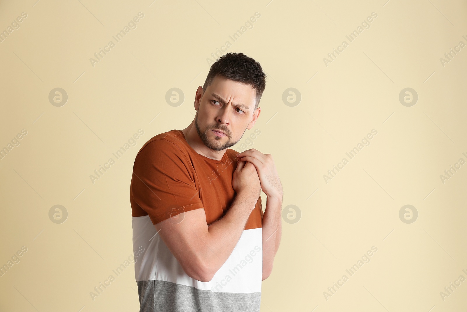 Photo of Greedy man hiding something on beige background