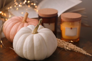 Pumpkins and candles on wooden board indoors