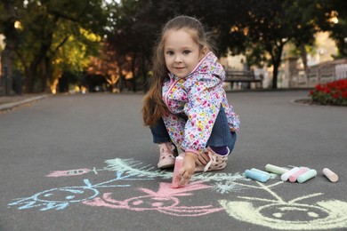 Child drawing family with chalk on asphalt