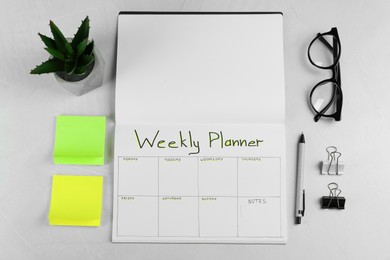 Flat lay composition of notebook with Weekly Planner on light grey table