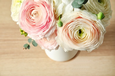 Photo of Beautiful spring ranunculus flowers in vase on wooden background, closeup