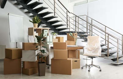 Photo of Cardboard boxes and furniture near stairs in office. Moving day