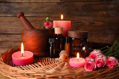 Beautiful composition with cosmetic products and pink roses in wicker tray. Aromatherapy treatment