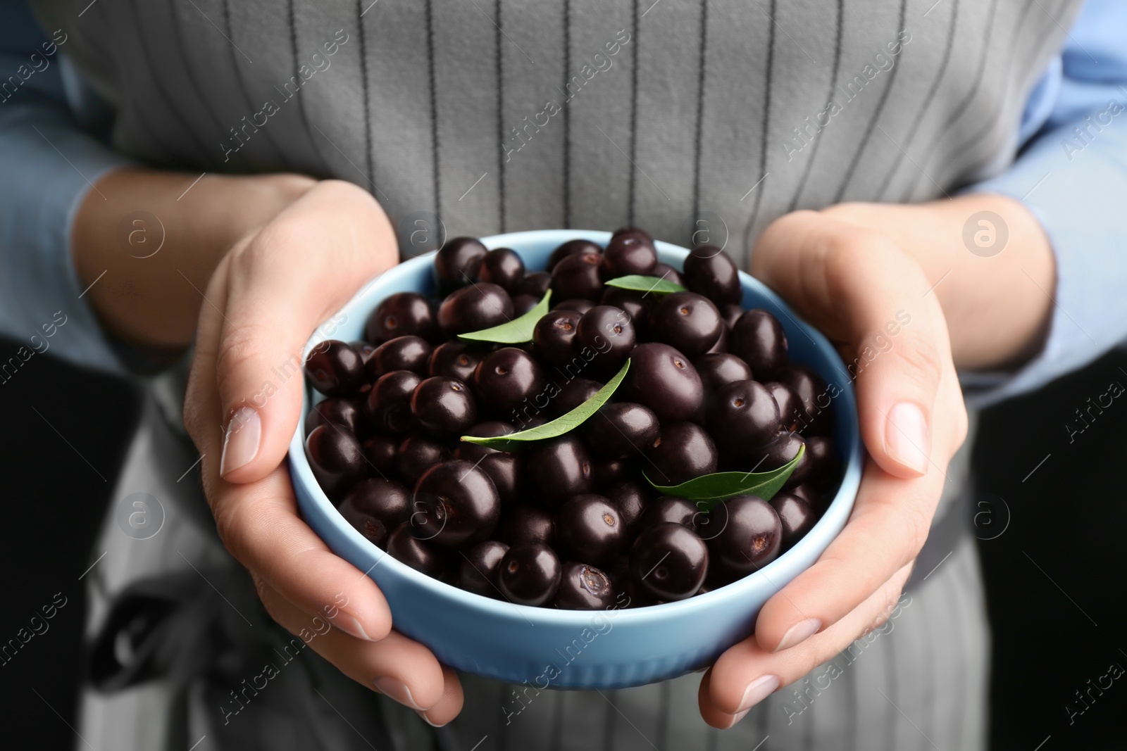 Photo of Woman holding tasty acai berries, closeup view