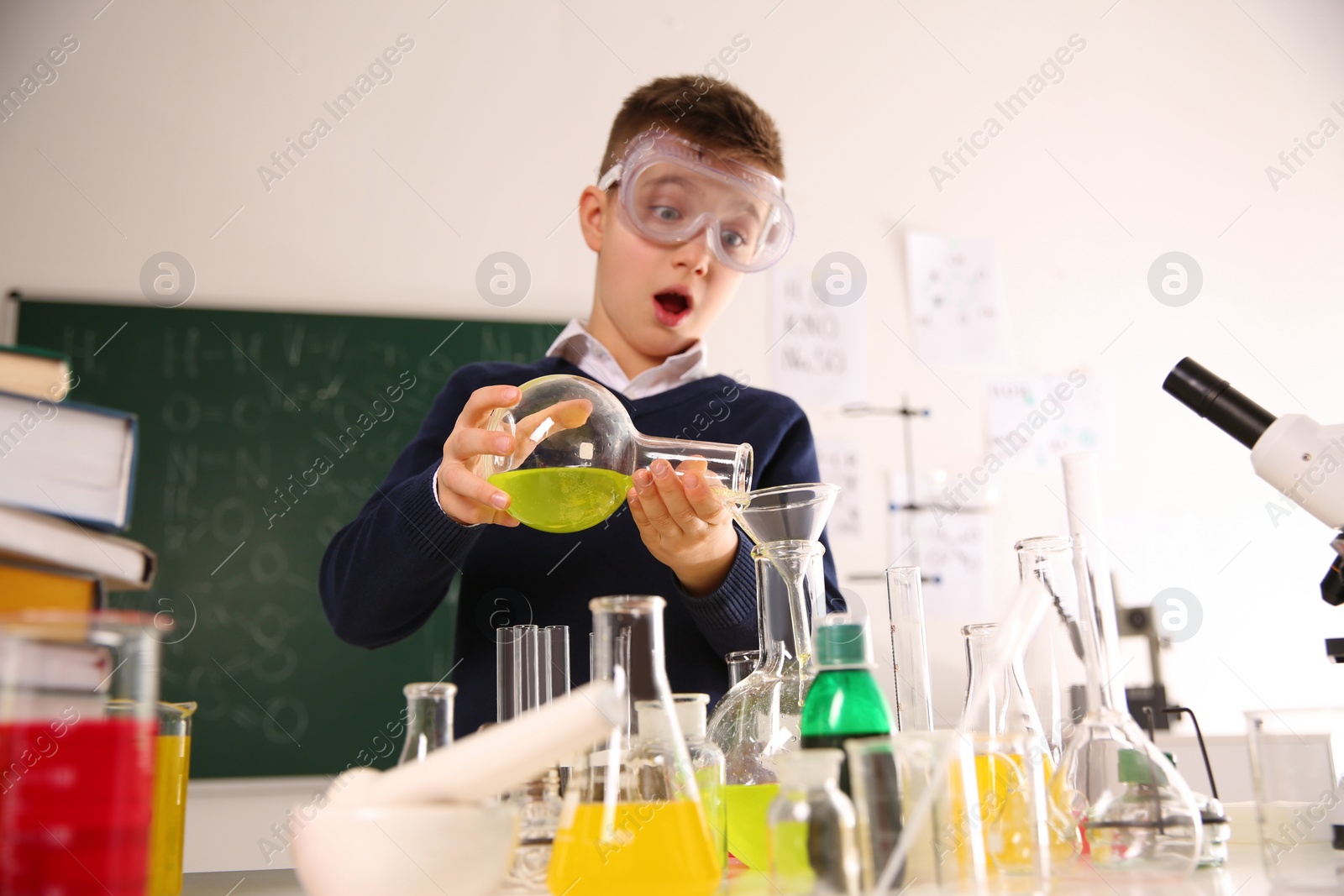 Photo of Schoolchild making experiment at table in chemistry class