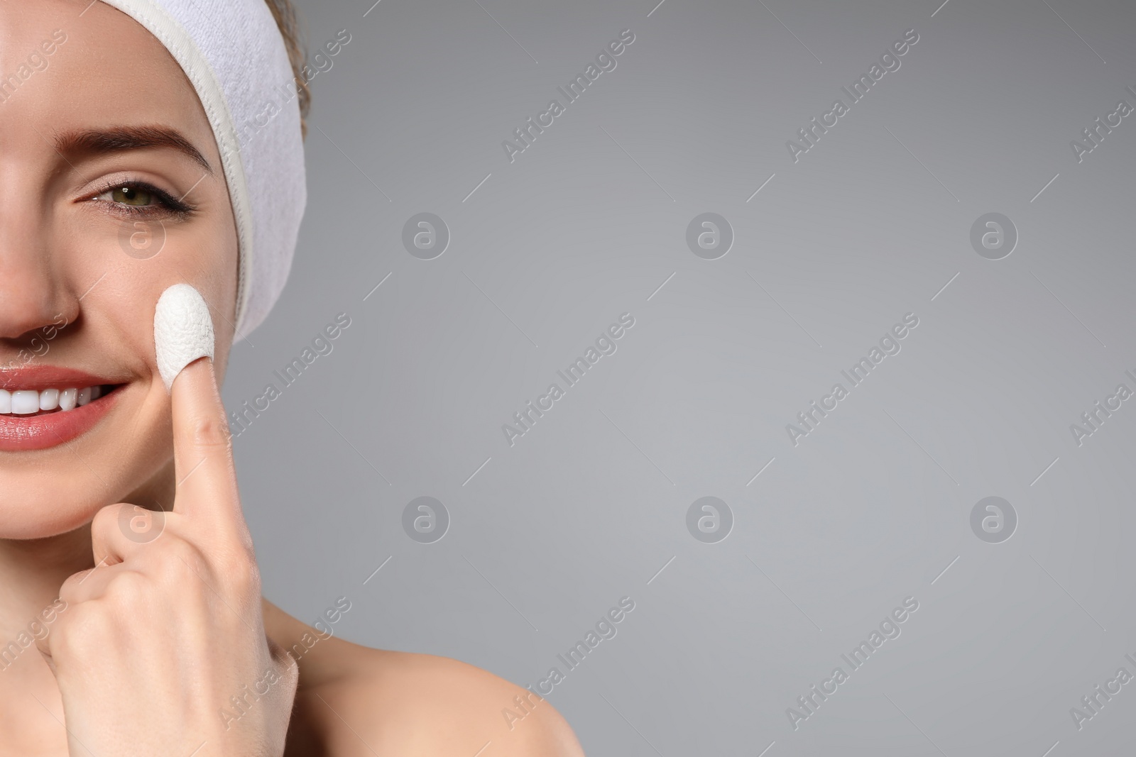 Photo of Woman using silkworm cocoon in skin care routine on grey background, closeup. Space for text